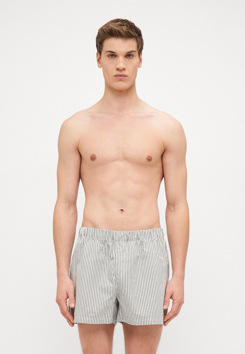 Shorts rayés en tissu de coton gris clair et blanc avec une taille élastique, conçus dans une coupe classique et décontractée.