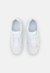 Valged sportlikud spordijalatsid helesiniste aktsentidega, tekstuuriga võrkkeelega, aukudega varbakast ja lame nöör, et tagada kindel istuvus.