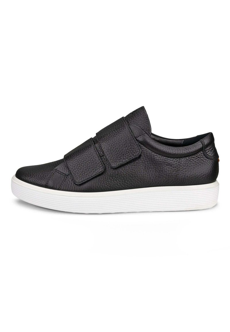 Baskets en cuir noir avec une surface texturée, deux bandes Velcro, un bout arrondi et une semelle en caoutchouc blanc avec un design strié.