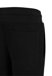 Pantalons de survêtement noirs avec une taille côtelée et une grande poche latérale ; matériau en coton doux et texturé avec une coupe classique.