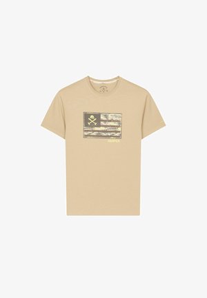 Camiseta beige de manga corta con una gráfica de bandera camuflada desgastada, un ícono de herramientas cruzadas y el texto "HARPER" en el pecho.