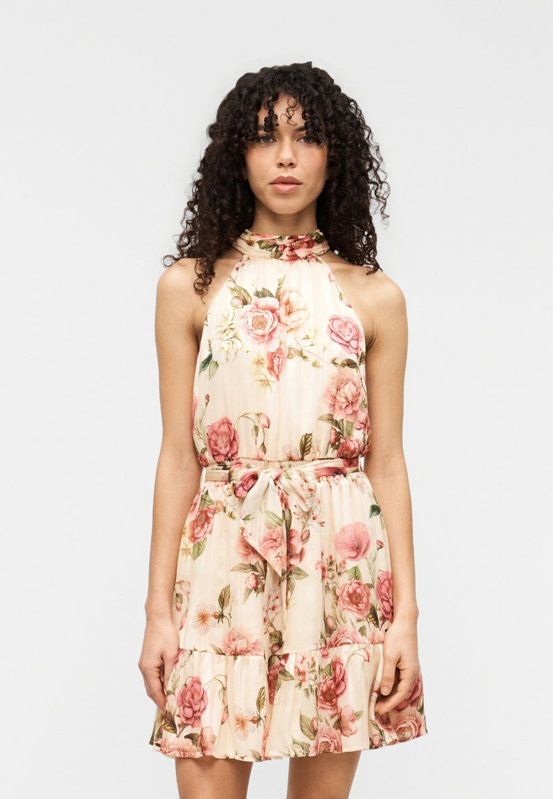 Φλοράλ φόρεμα με λαιμόκοψη halter σε κρεμ απόχρωση με ρόζ και πράσινα σχέδια, διαθέτει ζώνη στη μέση και φούστα με βολάν. Κατασκευασμένο από ελαφρύ ύφασμα.