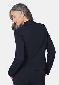 Zwart op maat gemaakte blazer met een reverskraag en lange mouwen, met een gladde, gestructureerde stof en een licht getailleerd ontwerp.