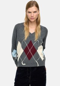 Szary sweter z dekoltem w serek, zdobiony diamentowym wzorem w kolorach burgundu, kremu i jasnoniebieskiego, z postrzępionymi brzegami. Dzianinowa struktura o luźnym kroju.