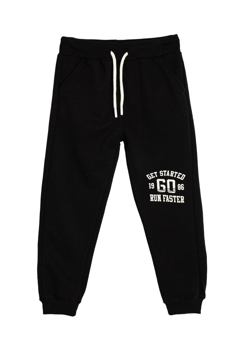 Zwarte sweatpants met een trekkoord in de taille, zijzakken en geribbelde manchetten, met witte tekst: "GA VAN START 1986 LOOP SNELLER."