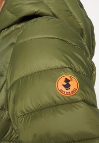 Olivengrøn pufferjakke med quiltet design og et rundt orange "Save The Duck" logo patch med en sort and silhuet.