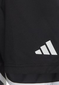 Schwarze Sportshorts aus glattem Material, die ein weißes Drei-Streifen-Logo und weißen Saum am Hemd aufweisen.