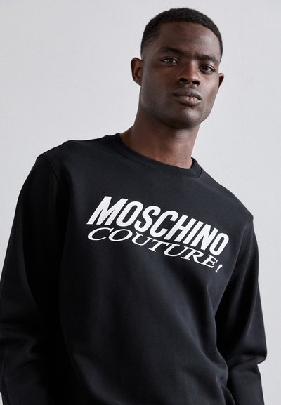 Sweat-shirt noir en coton, arborant un texte blanc audacieux "MOSCHINO COUTURE !" sur le devant. Conception classique à col rond et manches longues.