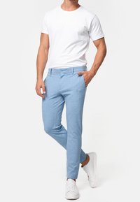 Pantaloni slim-fit azzurri realizzati in un tessuto misto cotone. Presentano una chiusura con bottone, tasche frontali e una texture liscia. Abbinateli a una t-shirt bianca.