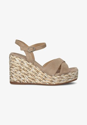 Beige suède wedge sandalen met een crisscross bandontwerp, voorzien van een gevlochten jute hak en een verstelbare enkelband met een zilveren gesp.