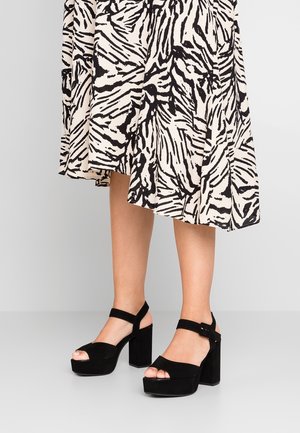 Zwarte suède platform sandalen met een chunky hak en open teen design. Voorzien van een brede band en een verstelbare enkelgesp voor een veilige pasvorm.