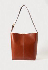 Brūna ādas rokassoma ar gludu tekstūru, vertikālu šuves detaļu un vienu regulējamu siksnu. Soma ir minimālistiska dizaina.