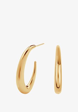 Złote kolczyki o zakrzywionym, wydłużonym kształcie, z błyszczącym wykończeniem i cienkim trzpieniem do mocowania.