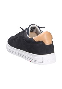 Schwarze Wildledersneaker mit einer weißen Gummisohle, lederner Akzent am Fersenbereich und schwarzen Schnürsenkeln. Das Innenfutter ist in einem hellbraunen Farbton gehalten und enthält ein Markenlabel.