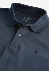 Polo majica od pamuka u mornarskoj plavoj boji s teksturiranim uzorkom, s dvostrukim dugmetom i izvezenim logotipom na prsima. Dizajn s regularnim krojem.