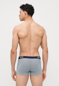 Boxers courts à motif géométrique en bleu marine, rouge et blanc. Ceinture élastique avec logo "BOSS". Design doux et ajusté.