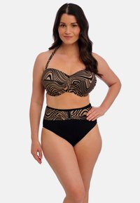 Bikini de alta cintura con un patrón ondulado en negro y beis. La parte superior tiene un diseño estructurado con tirantes ajustables y un detalle de cierre.