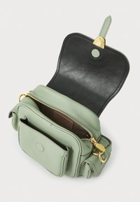 Sac bandoulière en cuir vert avec une fermeture éclair dorée, un fermoir magnétique et une doublure intérieure noire. Comprend une poche avant et une étiquette logo à l'intérieur.