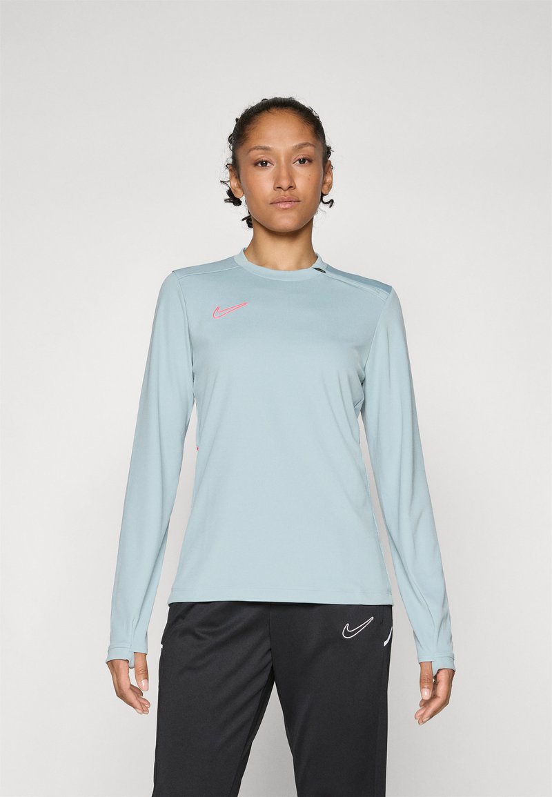 Svetlomodrá dlhá športová košeľa s okrúhlym výstrihom, na hrudi s ružovým logom Nike a športovým, priliehavým strihom.