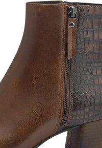 Bottine en cuir marron avec texture crocodile sur le côté, dotée d'une fermeture éclair et d'un talon empilé pour plus de hauteur.