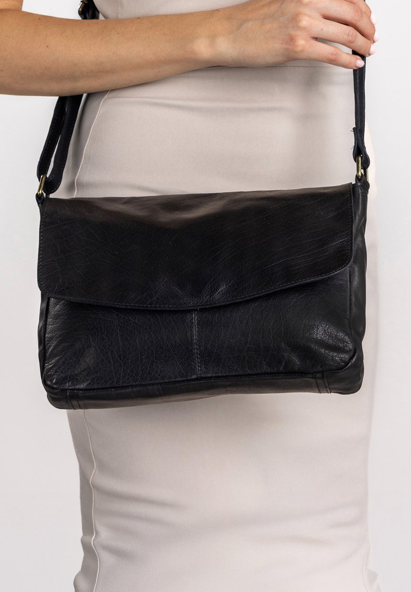 Black leather shoulder bag with a flap closure, smooth texture, and an adjustable strap. Simple design with no visible hardware accents.
