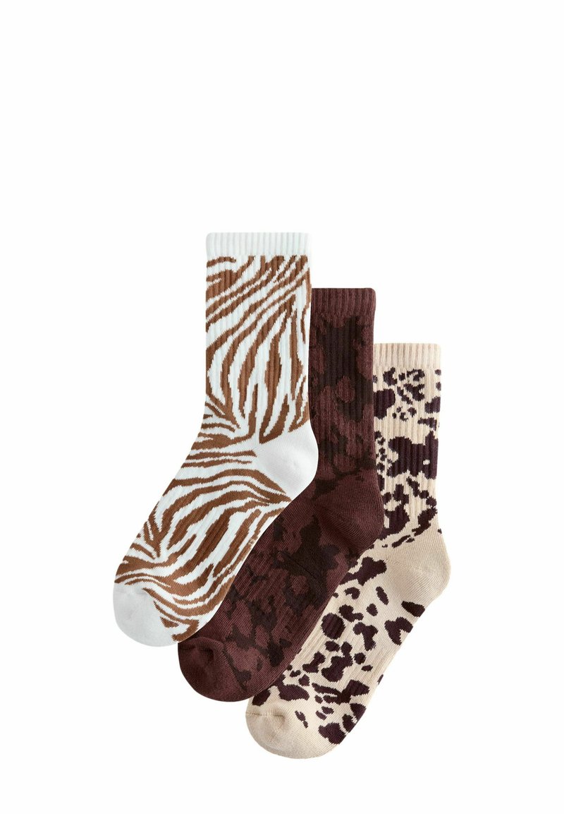 Tre par strømper: et med brun og hvid zebra-stribe, et i ensfarvet mørkebrun, og et i beige med brune abstrakte mønstre.