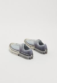 Niedrig geschnittene Sneakers mit einem Farbverlauf von Blau zu Grau, aus Canvasmaterial, mit Gummisohlen und "Feng Chen Wang" Branding an der Seite.