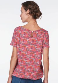 Kurzärmlige Bluse mit floralem Muster in Pink, Rot und Blau, mit einem Ausschnitt im Rücken und einer lockeren Passform.