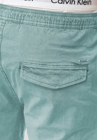 Svijetlozelene pamučne kratke hlače s stražnjim džepom i detaljem logotipa. Elastična traka sadrži vidljiv bijeli logotip Calvin Klein.