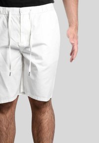 Pantaloni corti bianchi realizzati in tessuto leggero con vita elastica, bottone frontale e cordoncino. Taglio dritto con tasche laterali.