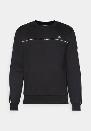 Čierna mikina s dlhými rukávmi, okrúhlym výstrihom, bielymi akcentovými pruhmi pozdĺž ramien a bokov, s malým logom Lacoste na hrudi.