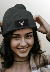 Knitted black beanie with a textured pattern and a rectangular patch featuring a white deer head graphic.