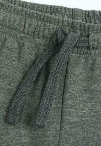 Grüne, weiche Baumwoll-Sweatpants mit elastischem Bund und geflochtenem Kordelzug. Sie verfügen über einen strukturierten Stoff und gerippte Kanten.