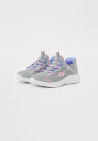 Zapatillas deportivas gris sin cordones con acentos en rosa y azul, parte superior de malla, suela texturizada y suela exterior blanca en contraste. Cordones visibles, diseño ligero.