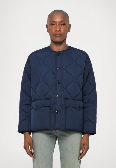 Giacca trapuntata blu navy con collo rotondo, chiusura a bottoni, due tasche frontali e un motivo testurizzato. Realizzata in un materiale morbido e imbottito.