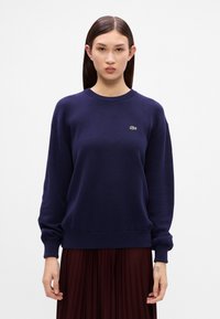 Námornícky modrá mikina vyrobená z bavlny; okrúhly výstrih, rebrované manžety a lem; na hrudi má malé zelené logo Lacoste.