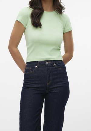 Jasnozielony prążkowany top z krótkim rękawem, zestawiony z ciemnoniebieskimi, wysokim stanem jeansami o klasycznym designie z pięcioma kieszeniami i miedzianym przeszyciem.