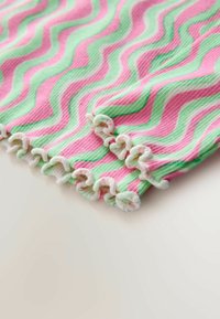 Top din țesătură reiată cu un model ondulat în roz și verde, având margini volanate albe. Textura subtilă adaugă un plus de interes vizual.