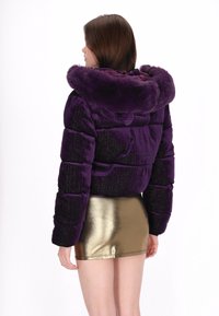 Fioletowa kurtka puchowa z futrzanym kapturem, o prążkowanej fakturze i elastycznych mankietach, w zestawieniu ze złotą metaliczną mini spódniczką.