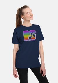 Granatowa bawełniana koszulka z krótkim rękawem z wielokolorową grafiką logo MTV, z napisem "MUZYKA TELEWIZJA" poniżej w białym kolorze. Luźny krój.