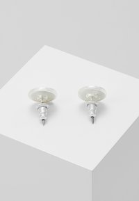 Clear acrylic stud earrings with silver-tone hardware, featuring a circular shape and smooth texture. Placed on a neutral background.