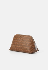 Borsa in pelle marrone con texture e un motivo geometrico, chiusura con zip e forma leggermente triangolare. Finitura liscia e accessori in argento lucido.