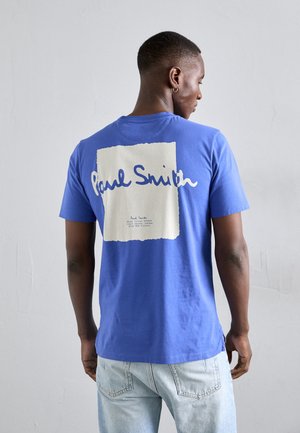 Blauwe katoenen t-shirt met een grote witte vierkant met de tekst "Paul Smith" en details op de achterkant. Korte mouwen en ronde halsontwerp.