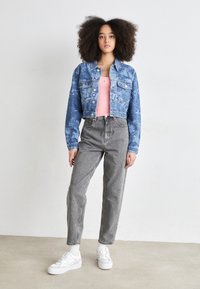 Denim jacket with palm tree print, blue color, cropped design, paired with a pink tank top, gray high-waisted jeans, and white sneakers.