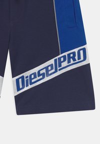 Bermudas azul-marinho com um atrevido logótipo "DieselPRO" em branco e azul, com detalhes em cinza claro e um corte atlético elegante.