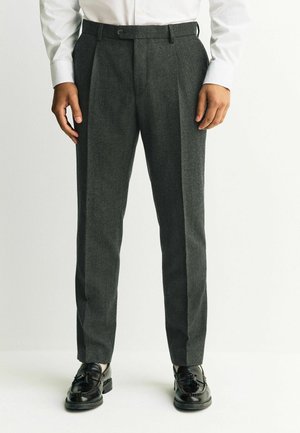 Dark gray wool trousers with a tailored fit, featuring a pleated front and side pockets, paired with black leather shoes.