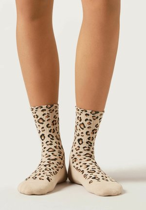 Beige Knöchelsocken mit einem schwarz-braunen Leopardenmuster, gerippter Textur und nahtloser Zehenkonstruktion.