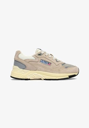 Sneaker beige e grigia con pannelli in mesh e suede, suola imbottita crema, lacci e toppa logo con bandiera americana sul lato.