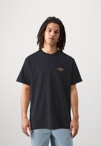 Black cotton t-shirt with a loose fit, round neck, and a small, diamond-shaped graphic in orange and brown on the left chest area.