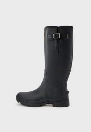 Botte en caoutchouc noire étanche avec une boucle ajustable, une surface texturée, une forme légèrement incurvée et une semelle robuste pour une meilleure adhérence.